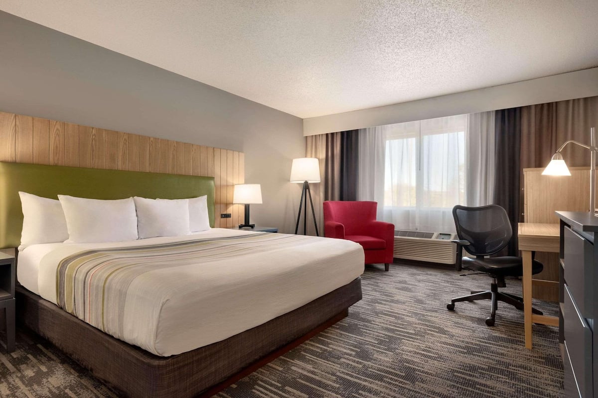 Een hotelkamer met een groot bed, een bureau, een stoel en een vloerlamp.