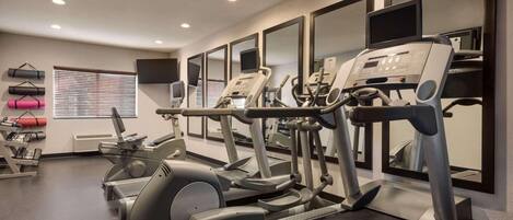 Un gimnasio con cintas de correr, elípticas y pelotas de ejercicio.