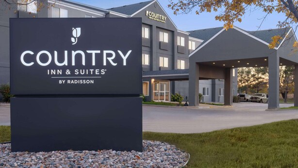 A sign for Country Inn & Suites by Radisson with a modern building in the background.