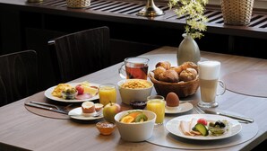 Een ontbijttafel met verschillende soorten eten, een bloemenvaas en een wereldbol op een vensterbank.