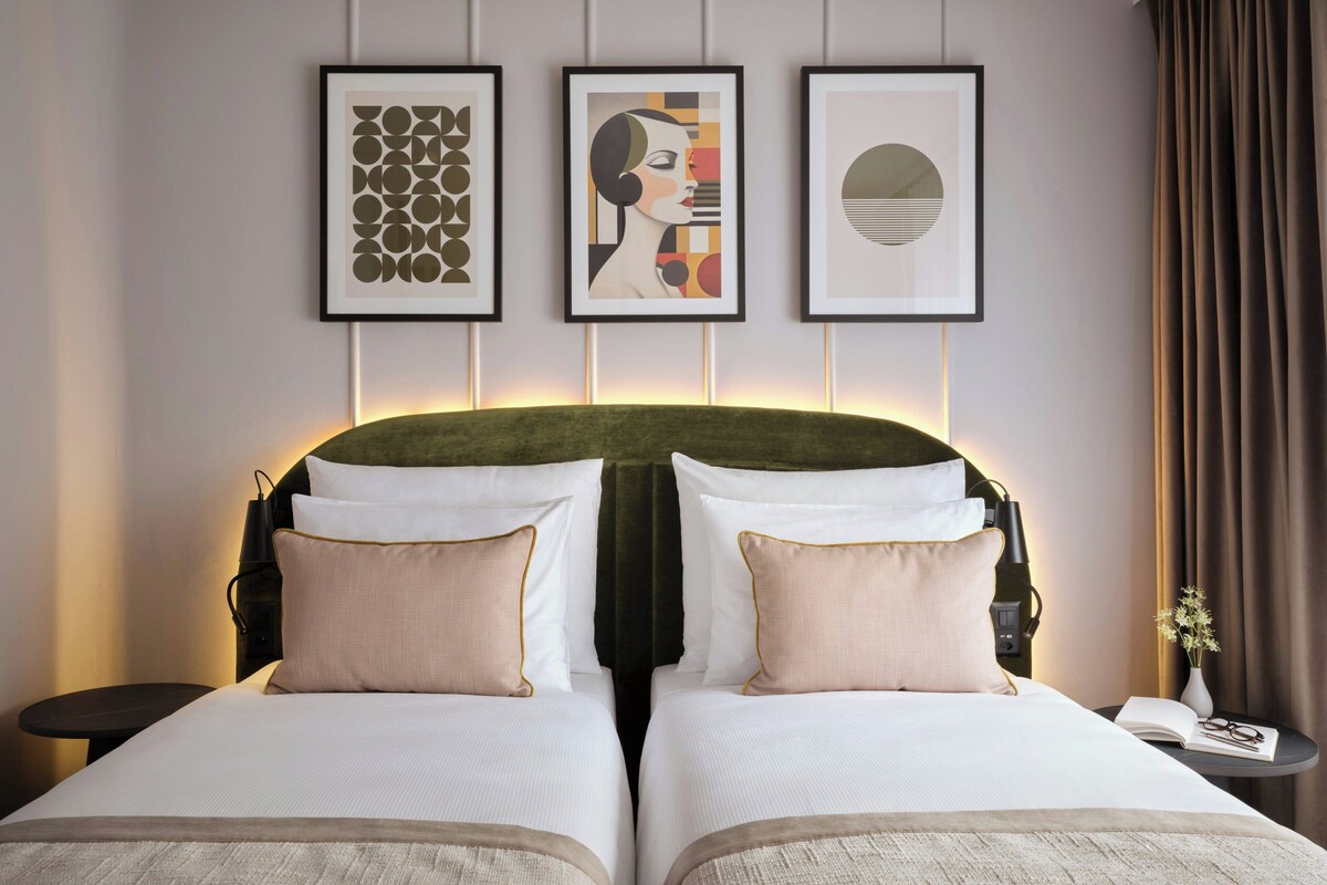 Una cama doble con dos almohadas, un cabecero y una mesita de noche con una lámpara.