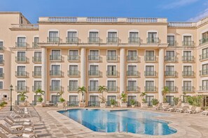 Una piscina al aire libre, sombrillas, sillones reclinables de piscina