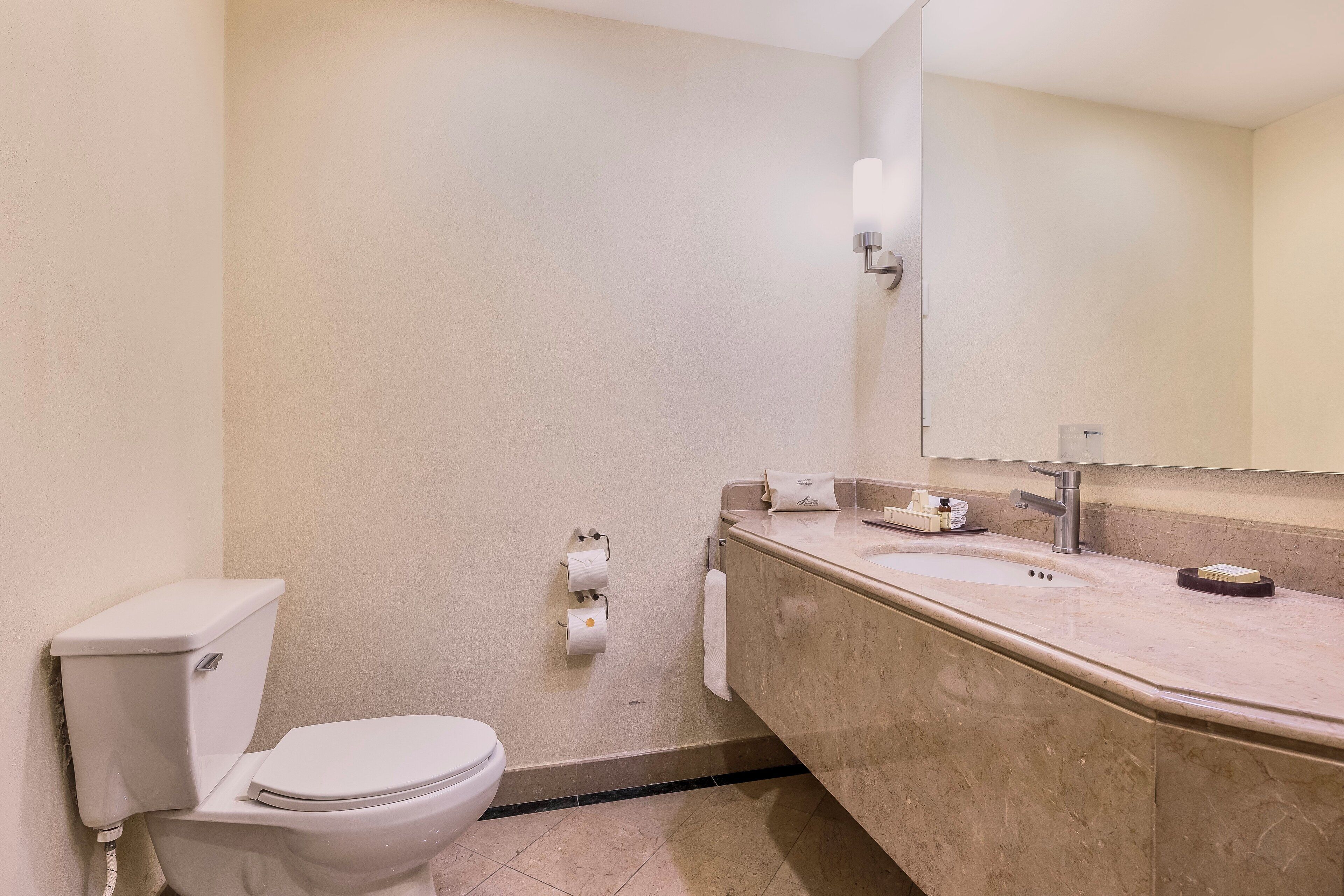 Un baño moderno con inodoro, lavamanos y espejo.