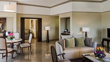 Habitación de hotel con comedor, sofá, mesa de centro y televisor.