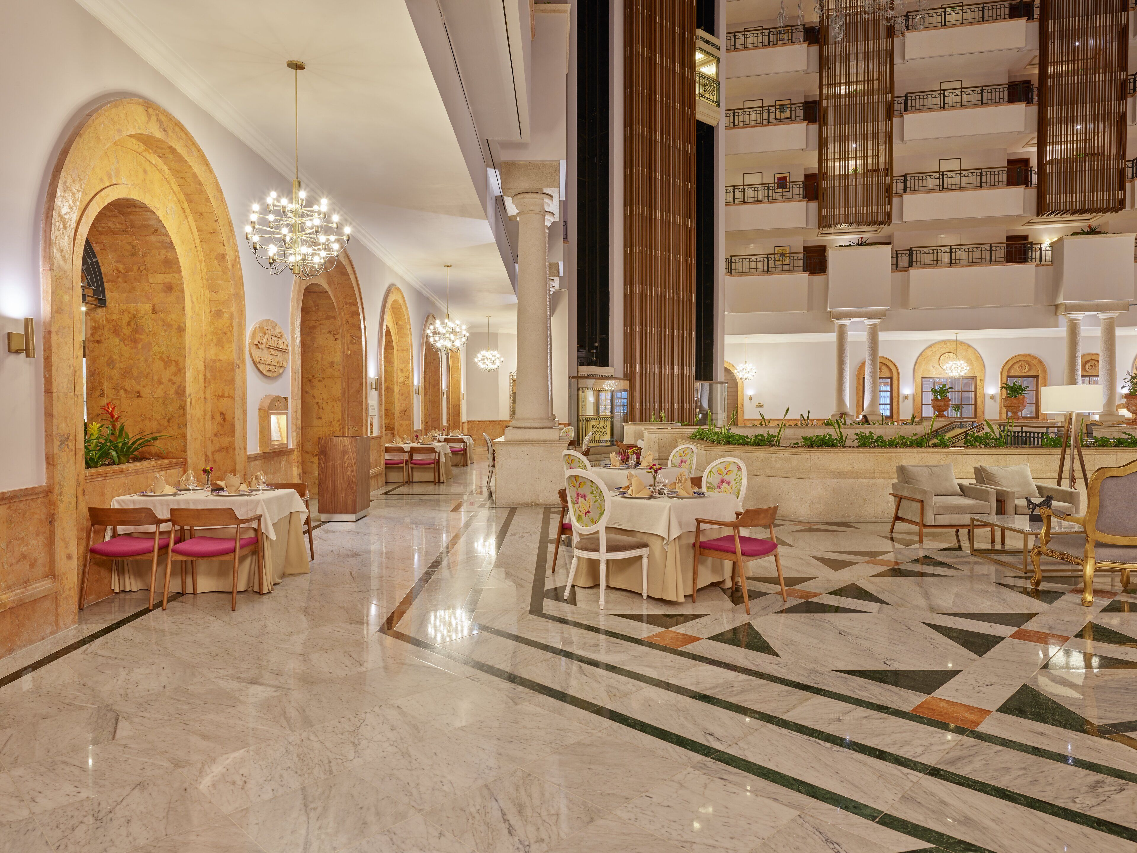 Eine großzügige Lobby mit Marmorböden, mehreren Essbereichen und einer zentralen Sitzecke mit Sofas und Tischen.