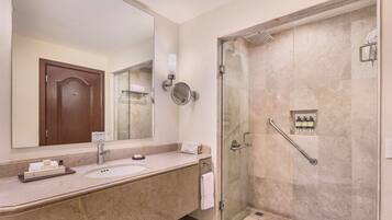 A bathroom with a large mirror, a sink, a shower with a glass door, and a towel rack.