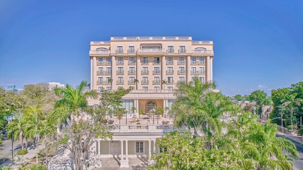 Um hotel grande, de vários andares, com fachada simétrica, diversas varandas e uma entrada central.