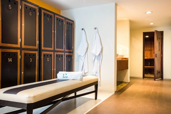 A hotel room with a massage table, a bench, and a row of lockers numbered 3 to 14.