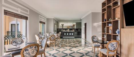 A dining area with a checkered floor, wooden chairs with floral upholstery, and a bar area in the background.
