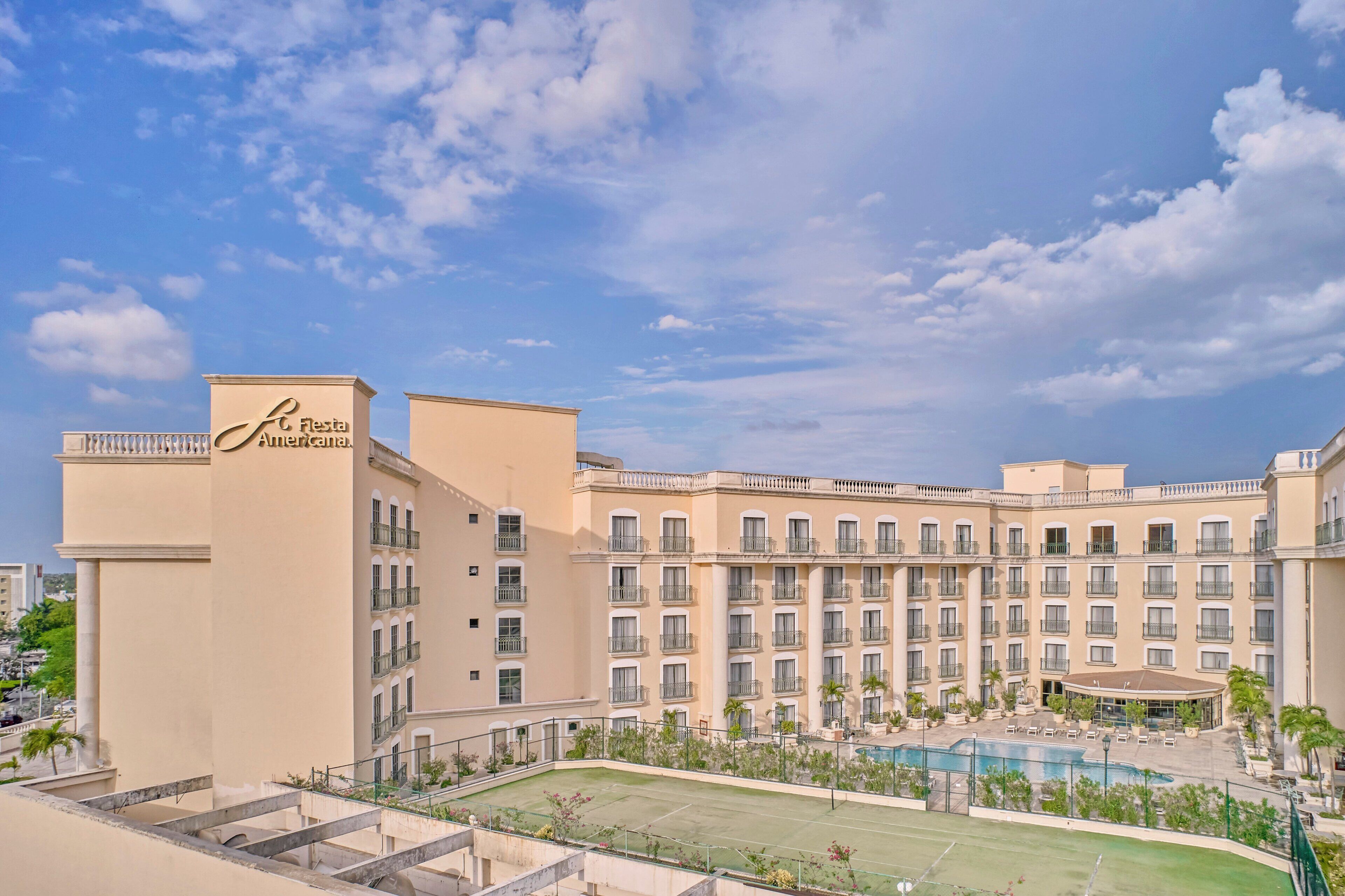A hotel with a large pool, multiple balconies, and a sign reading "Fiesta Americana."
