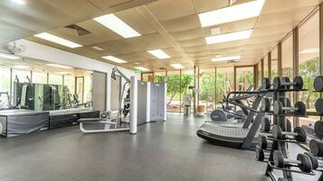 A gym with exercise equipment, large windows, and a ceiling fan.