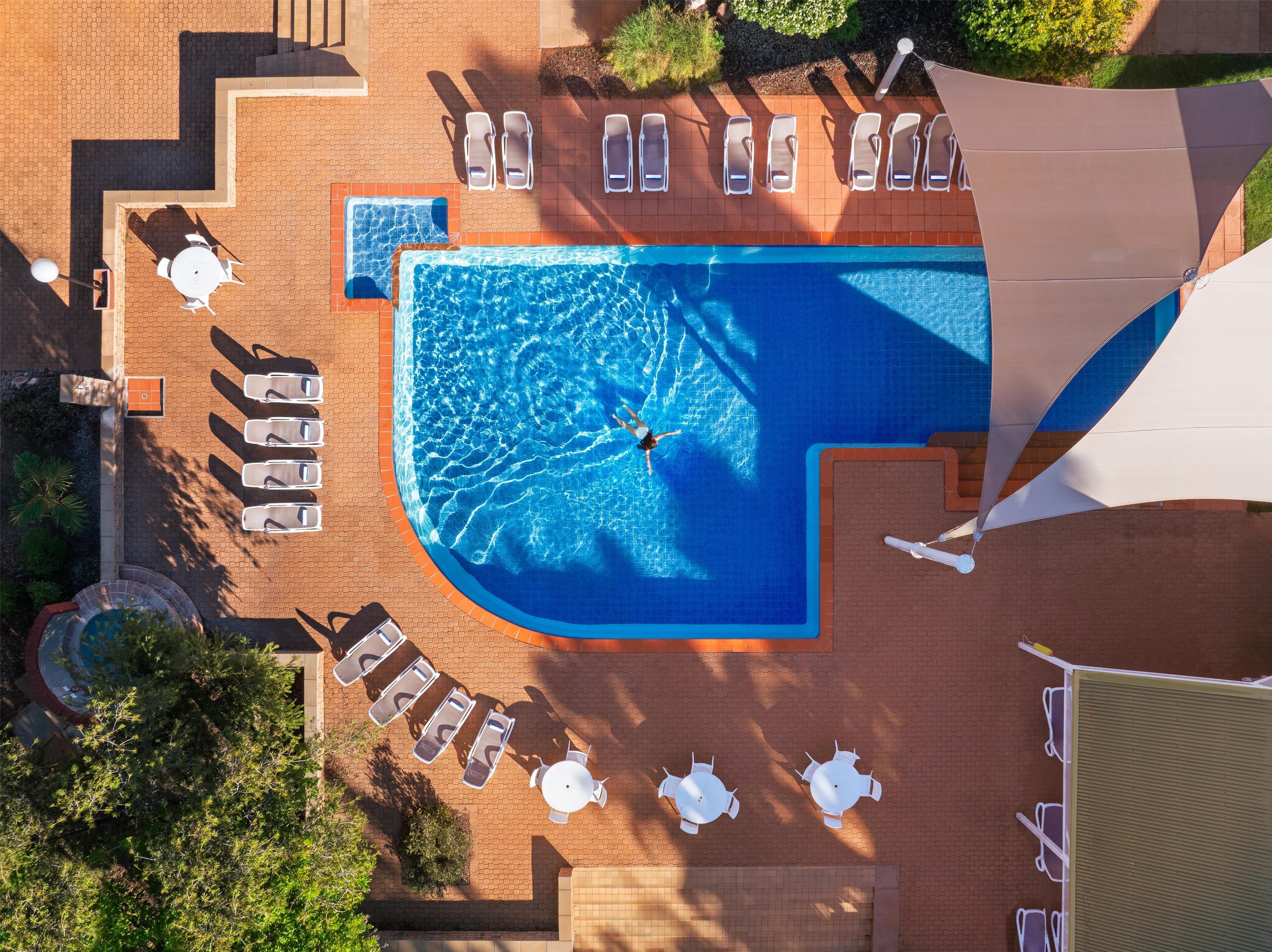 An aerial view of a swimming pool area with multiple sun loungers and a small pool.