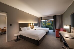 A hotel room with two beds, a desk, a chair, and a view of a mountainous landscape. - DoubleTree by Hilton Alice Springs (Desert Springs)