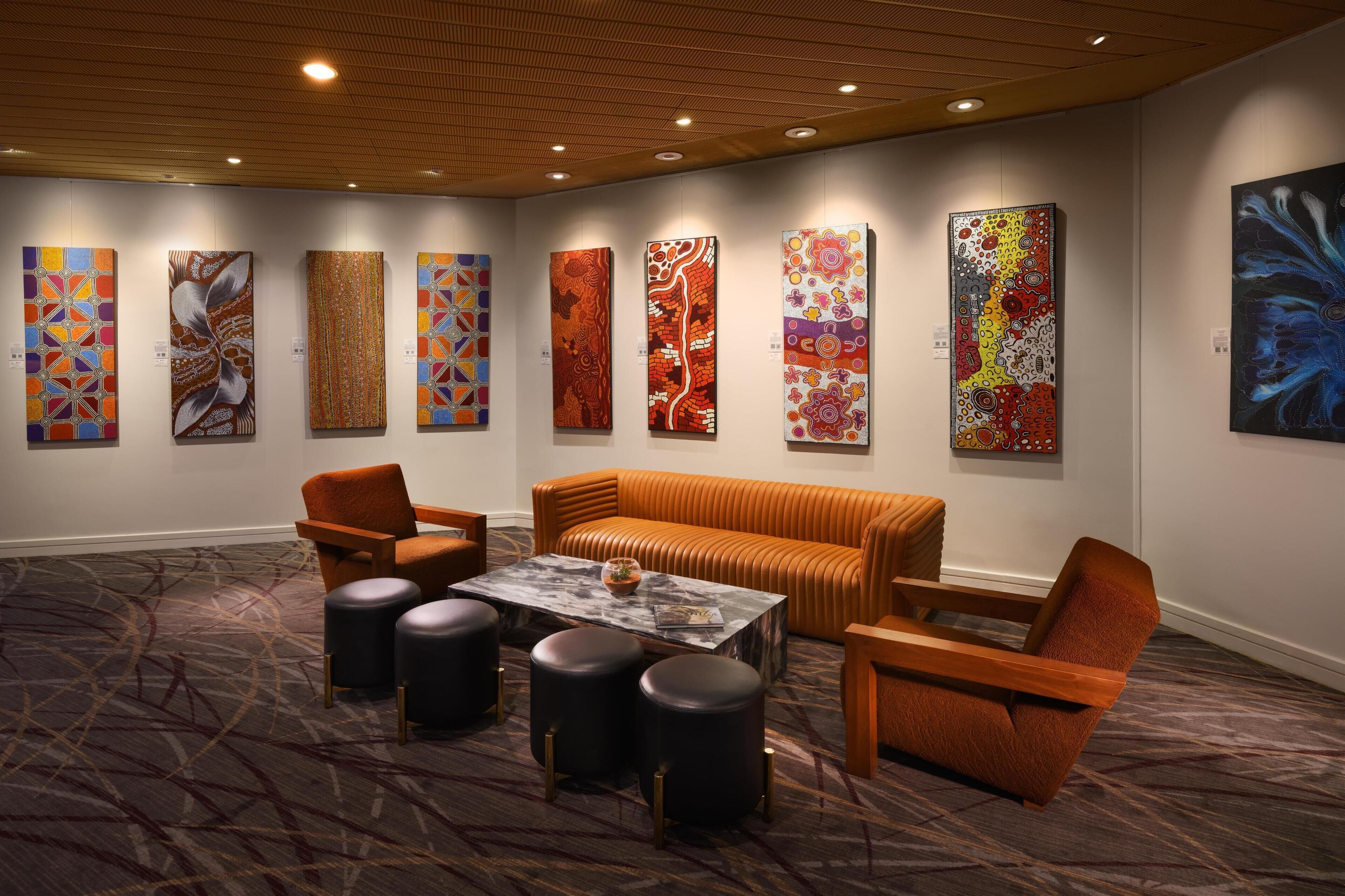 A modern art gallery with abstract paintings on the walls, a leather sofa, and a marble coffee table.