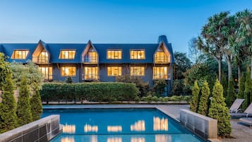 Experience the warm and inviting atmosphere of this luxurious hotel, featuring a symmetrical facade and serene pool area.