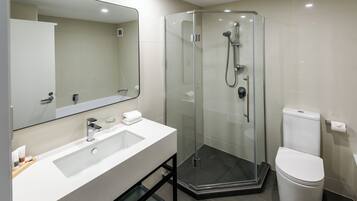 A modern bathroom with a glass-enclosed shower, a white sink, and a toilet.