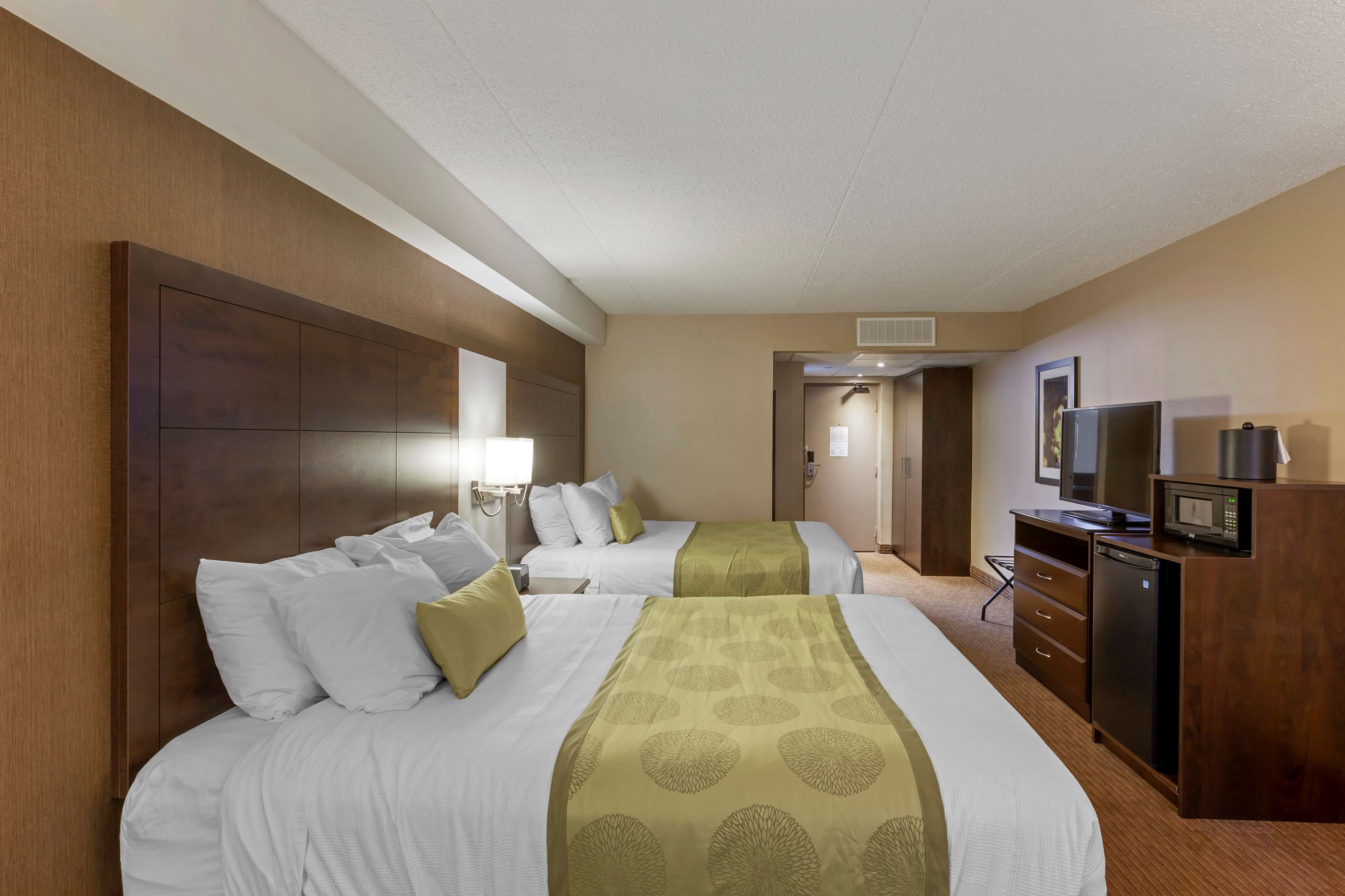 A hotel room with two beds, a TV, a microwave, and a small refrigerator.