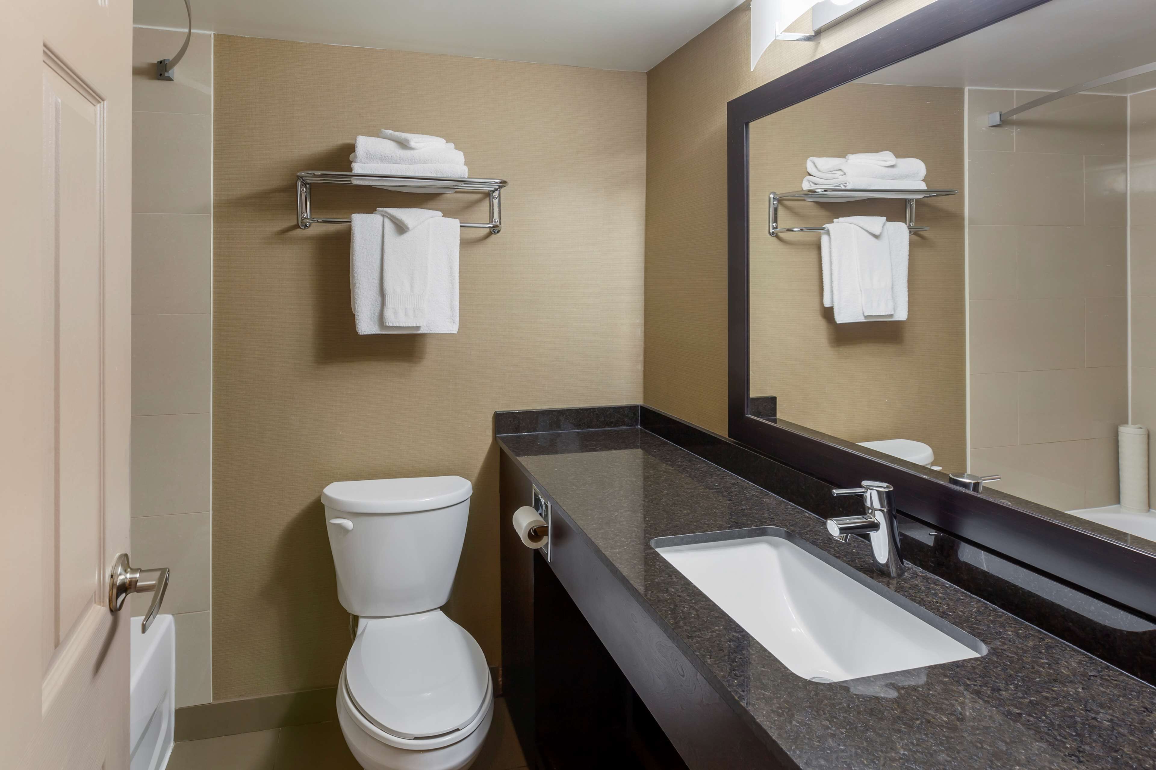 A modern bathroom with a toilet, sink, and towel racks.