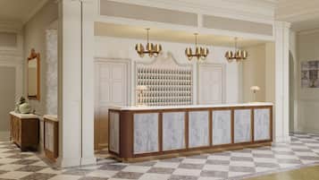A reception area with a marble counter, a wall of framed photographs, and a chandelier.