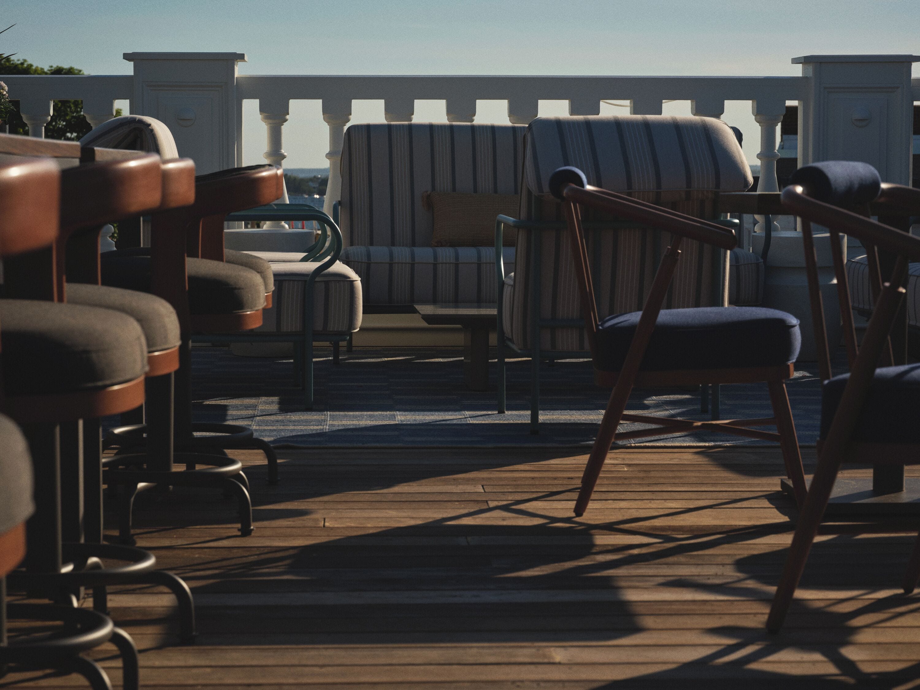 Une terrasse avec coin salon extérieur, comprenant des chaises et un canapé, située sous une balustrade blanche.