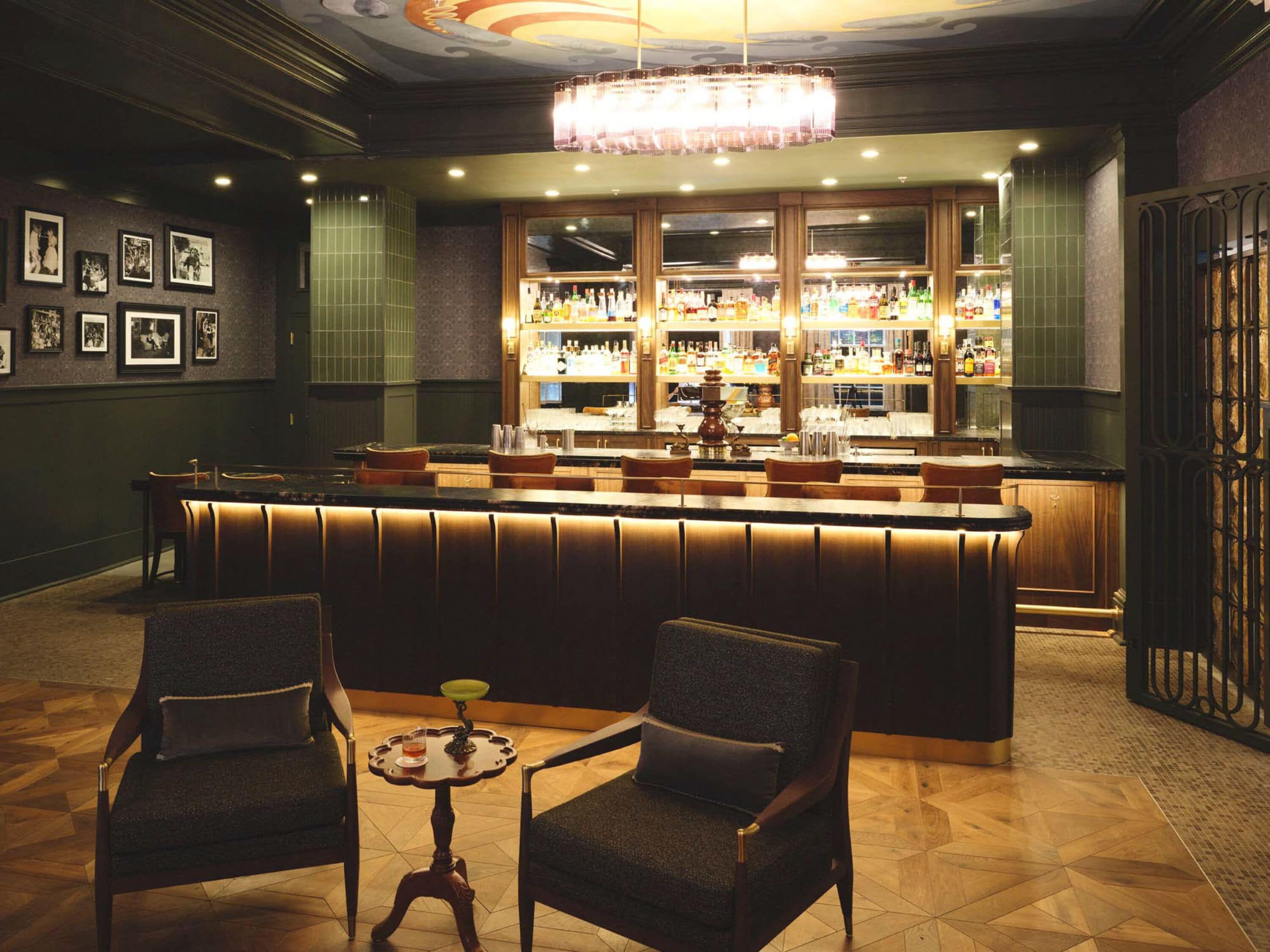 A bar area with a bar counter, seating, and a chandelier.