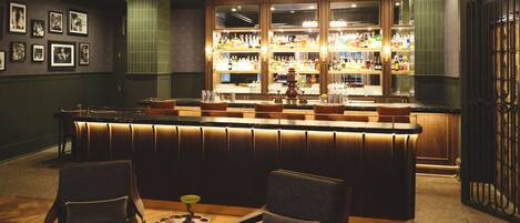 A bar area with a bar counter, seating, and a chandelier.