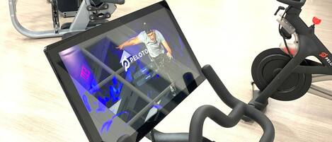 A gym with exercise equipment, a mirrored wall, and a Peloton bike.