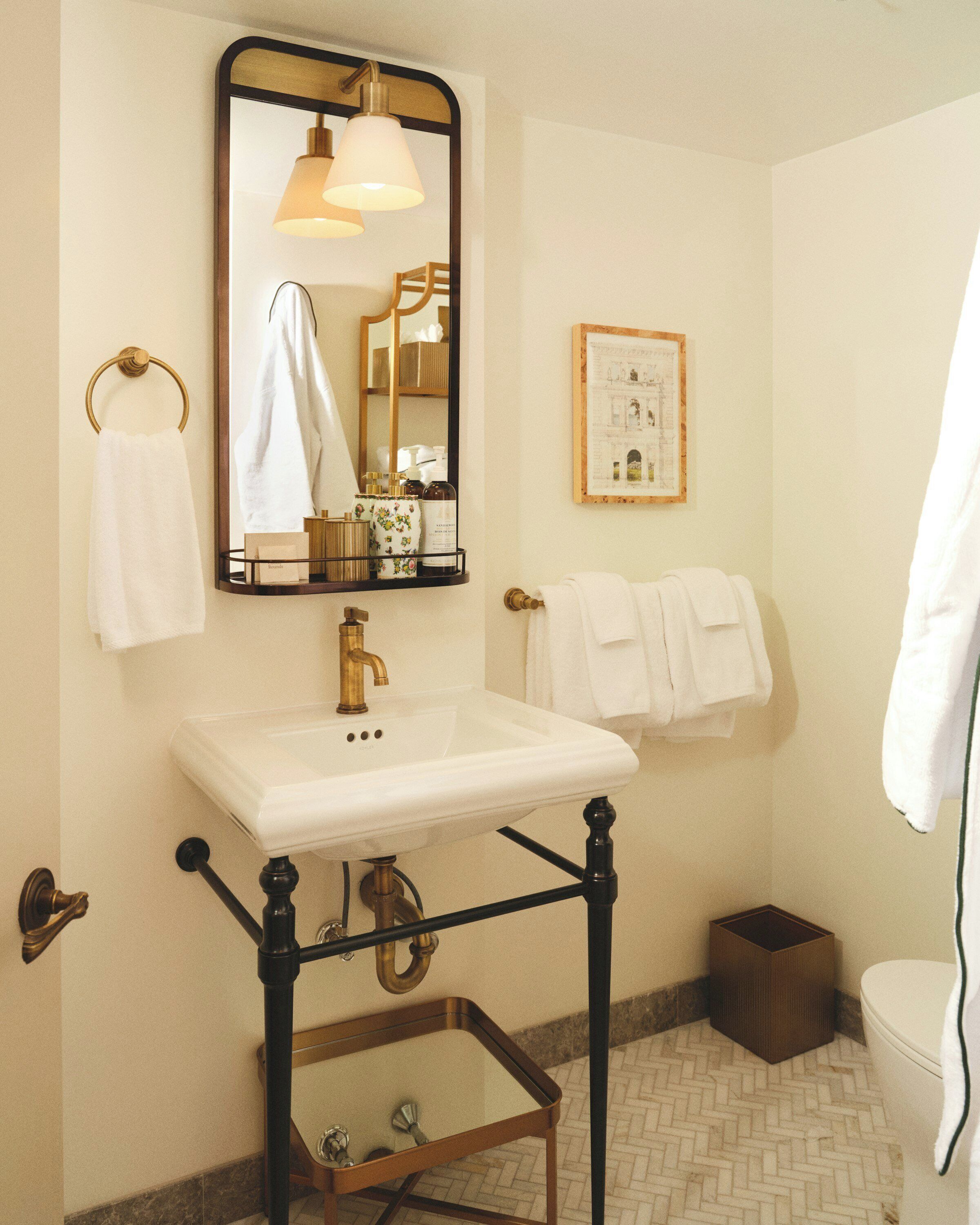 A bathroom with a white sink, a mirror, a towel rack, and a framed picture on the wall.