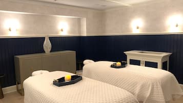 A hotel room with two beds, a vanity with a mirror, and a small table.