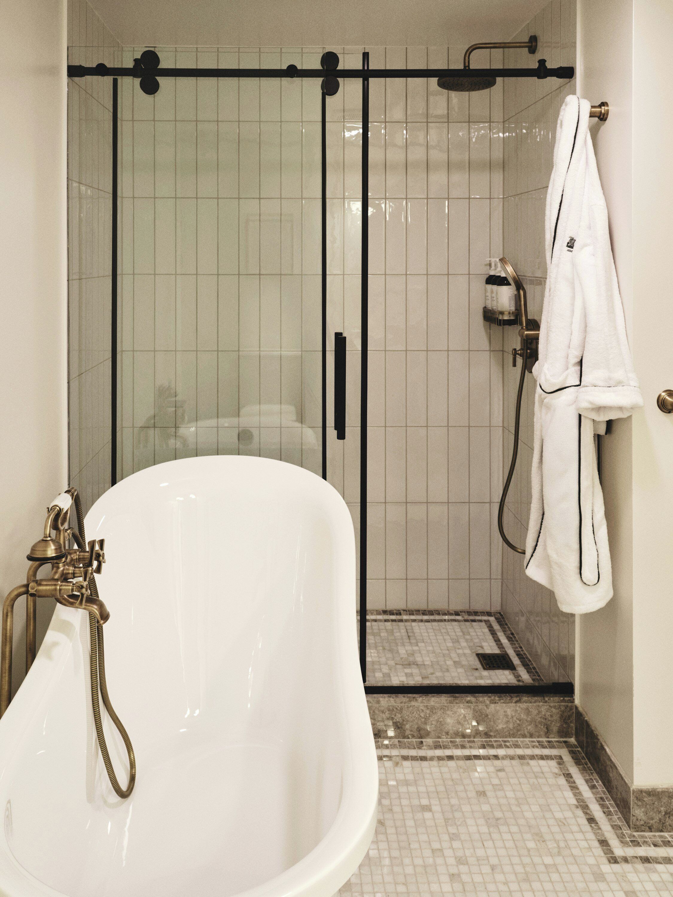 A bathroom with a bathtub, a glass-enclosed shower, and a towel rack.