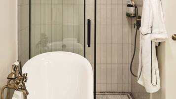 A bathroom with a bathtub, a glass-enclosed shower, and a towel rack.