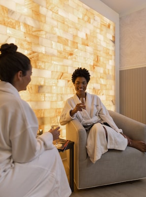 A spa room with a textured wall, a sofa, and a small table with a book and a glass. - Hotel Viking (Newport)