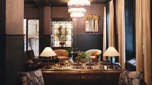 Un área de descanso acogedora con sofás de cuero, una mesita de centro, lámparas y objetos decorativos.