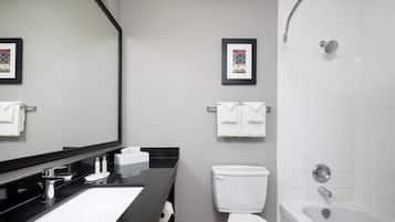 A modern bathroom with a black countertop, white sink, and a bathtub.