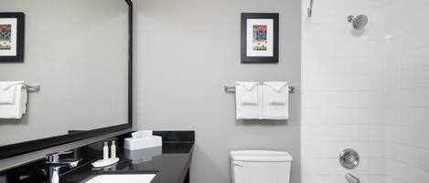 Un baño moderno con encimera negra, lavabo blanco y bañera.
