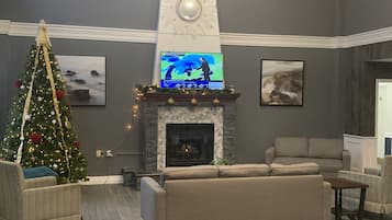 Una sala de estar con chimenea, un árbol de Navidad y un televisor mostrando un pronóstico del tiempo.