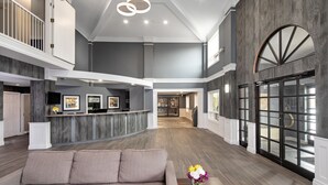 Un hall d’entrée spacieux avec un plafond haut, un comptoir de réception et un coin salon avec un canapé.