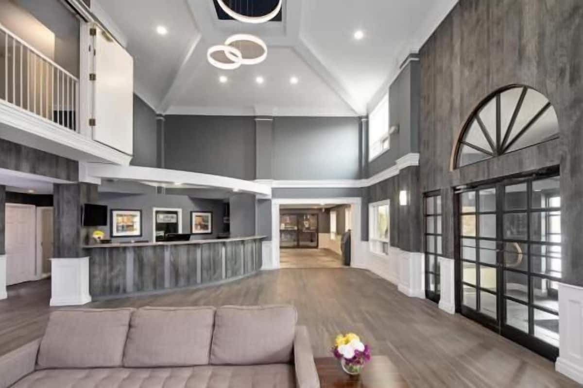 Eine geräumige Lobby mit hoher Decke, einem Empfangstresen, einer Couch und einem großen Fenster.