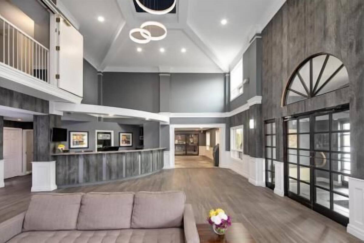 Eine geräumige Lobby mit hoher Decke, einem Empfangstresen, einer Couch und einem großen Fenster.
