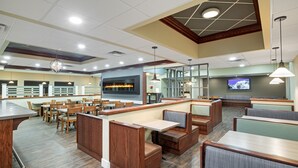 Un restaurant avec des banquettes et des tables, une cheminée et un téléviseur.