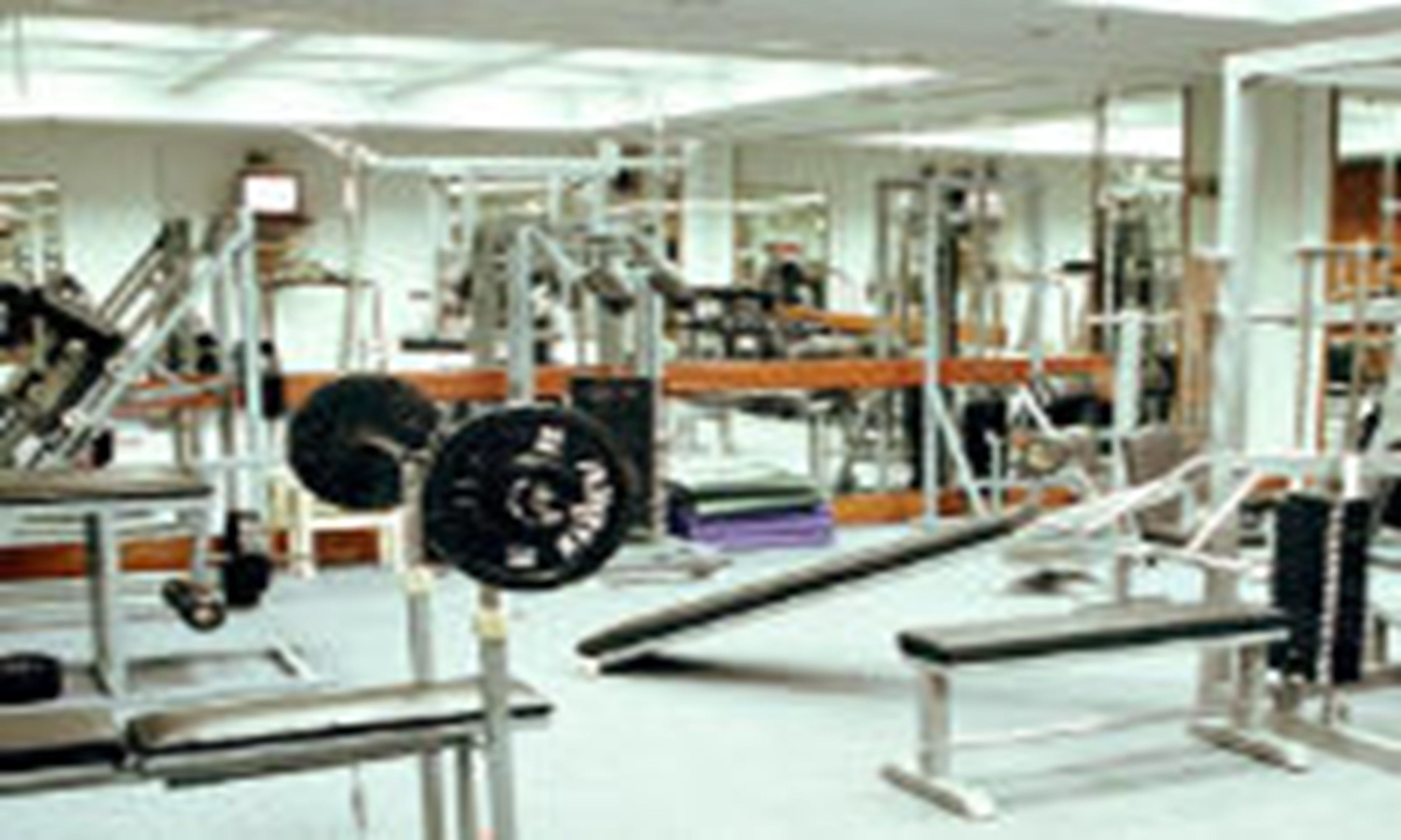 A gym with various exercise equipment including weight machines, benches, and a squat rack.