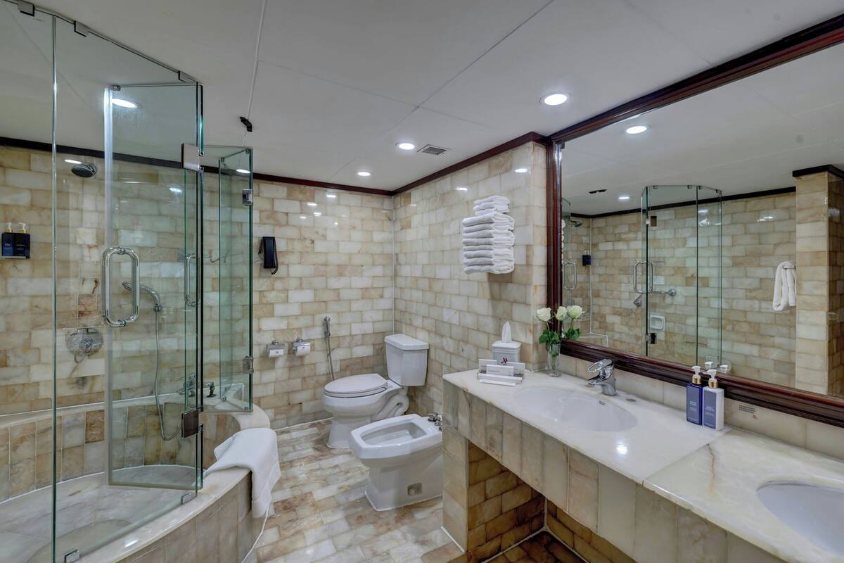A modern bathroom with a glass shower enclosure, a bidet, a toilet, and a vanity with a sink.