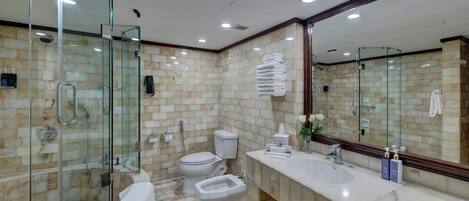 A modern bathroom with a glass shower enclosure, a bidet, a toilet, and a vanity with a sink.