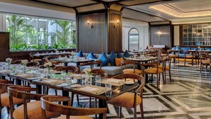 Un restaurante espacioso con varias mesas, sillas y una zona de estar con sofás y cojines.