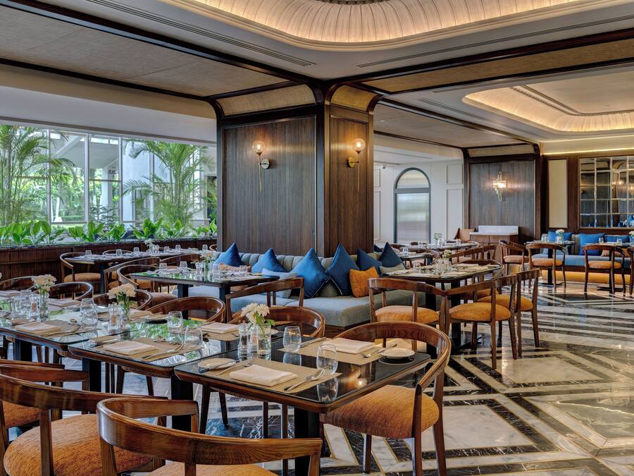 A spacious restaurant with multiple dining tables, chairs, and a seating area with sofas and cushions.