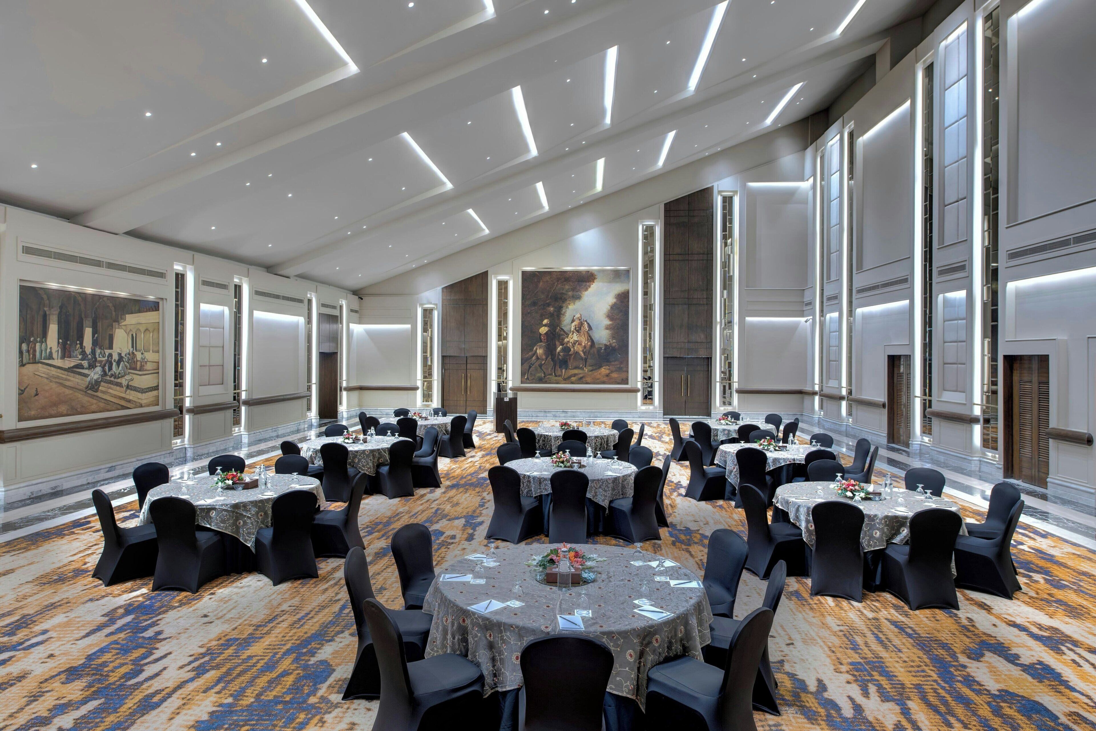 A conference room with multiple round tables, black chairs, and large windows.