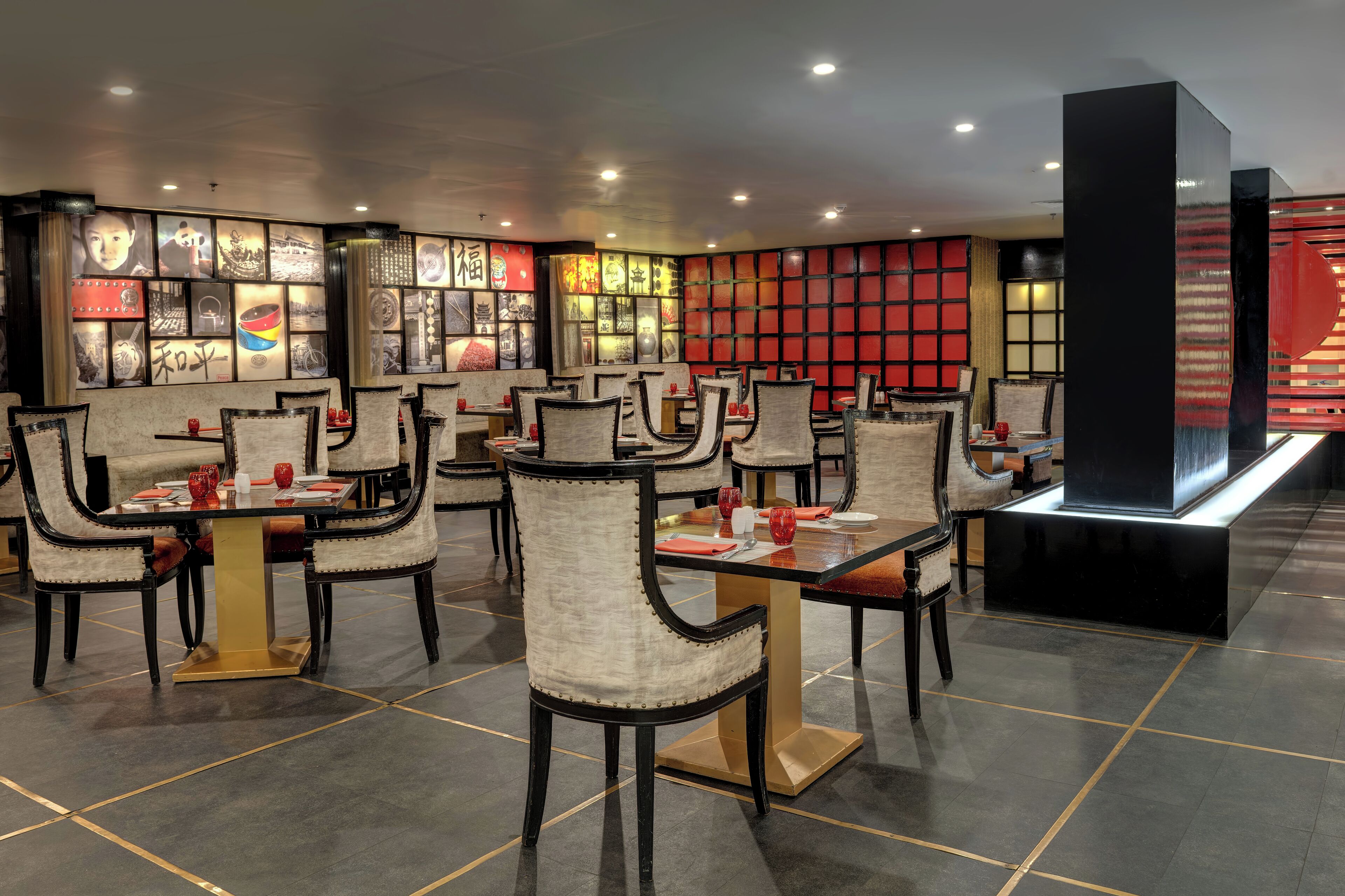 Un restaurant doté de nombreuses tables et chaises, d’un décor intérieur moderne et d’œuvres d’art accrochées aux murs.