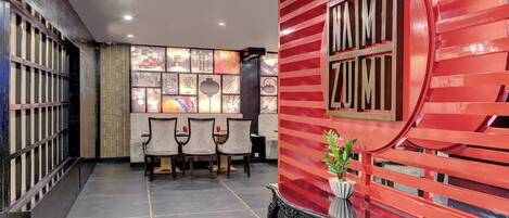 A lobby with a red wall, a reception desk, and a seating area with chairs.