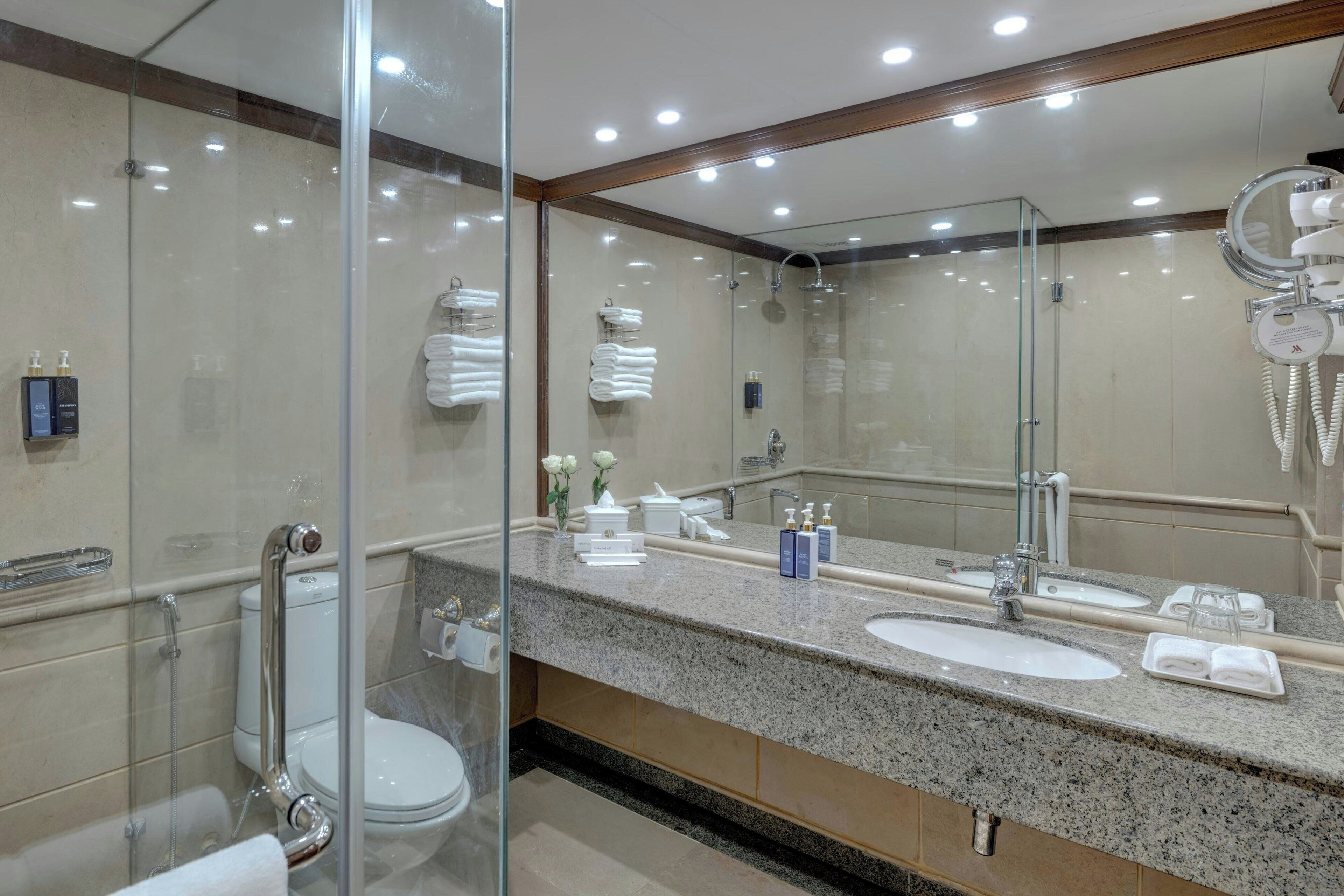 Un baño moderno con cabina de ducha de vidrio, tocador doble y un espejo grande.