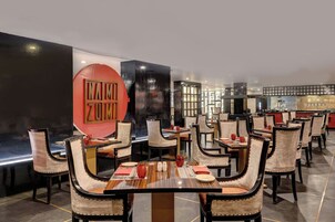 A restaurant with multiple dining tables and chairs, a large red sign, and a modern interior design.